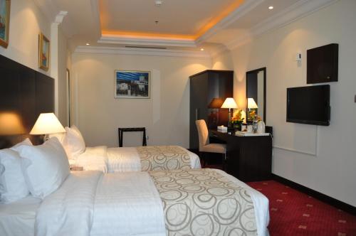 a hotel room with two beds and a desk at Musherib Hotel in Doha