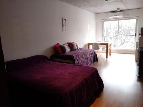 1 dormitorio con 2 camas, mesa y ventana en Apart con piscina a 200 mt Movistar Arena en Buenos Aires