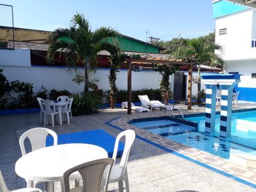 a patio with tables and chairs next to a swimming pool at Regine's Hotel in Itacoatiara