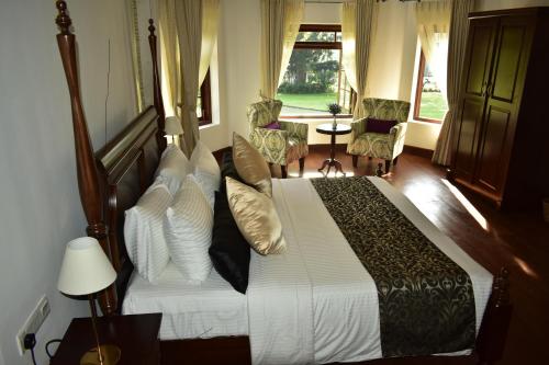 1 dormitorio con 1 cama con sábanas y almohadas blancas en Hill Cottage en Nuwara Eliya