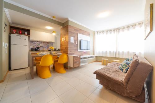 a kitchen and living room with a table and yellow chairs at GRAMADO SOLAR REAL - 2 APTS de 2 quartos no mesmo prédio, cada um comporta até 7 pessoas - IDEAL PARA GRUPOS - central - IDEAL PARA ANDAR A PÉ, nesta plataforma desde janeiro de 2016, oferecemos CREDIBILIDADE - seu PET é bem-vindo - GARAGEM COBERTA in Gramado