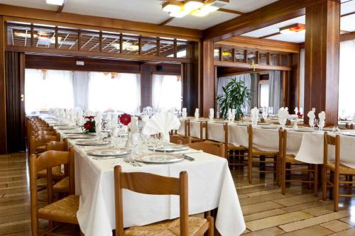 a long dining room with white tables and chairs at Hotel Dante in Ponte nellʼAlpi