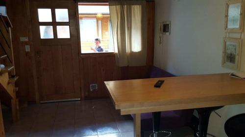 Habitación con mesa de madera y ventana. en 845 Teniente Ramayón en San Martín de los Andes