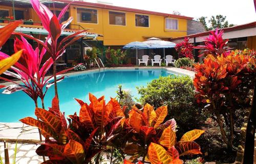 a swimming pool in front of a house with plants at Hotel Puerta del Sol - San Jose Airport in San José