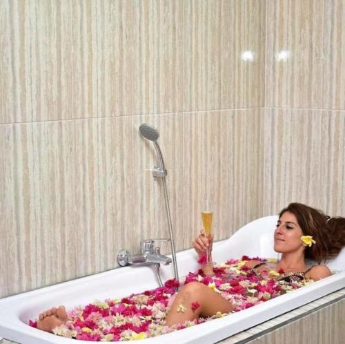 a woman sitting in a bath tub filled with flowers at The Barari Villas in Pemuteran