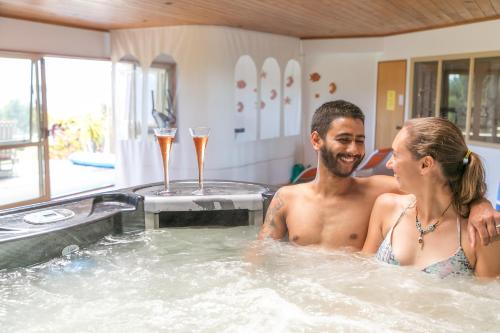 a man and woman in a hot tub with champagne glasses at Chalet Romantica in Paihia