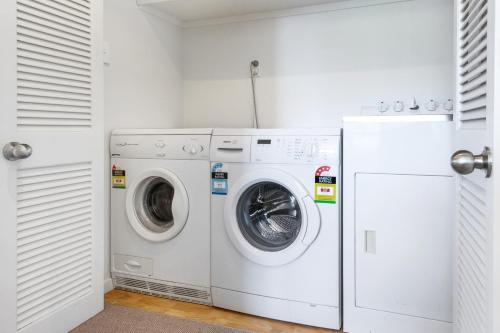 a white laundry room with a washer and dryer at Beachfront Enclosure Bay - Waiheke Unlimited in Oneroa