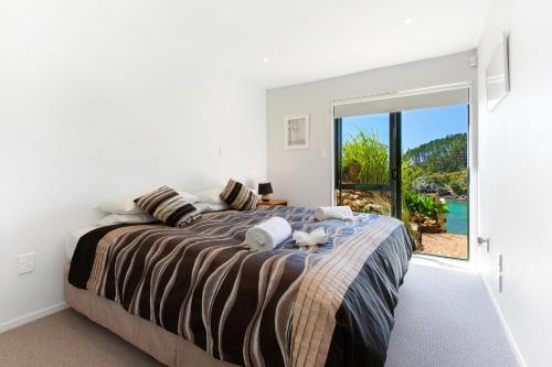 a bedroom with a bed with a view of the ocean at Beachfront Enclosure Bay - Waiheke Unlimited in Oneroa