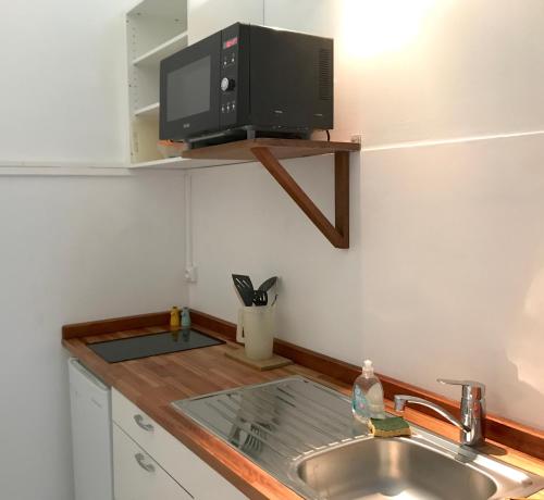 a kitchen with a sink and a tv on the wall at Gîtes de Checheti in Trois-Rivières