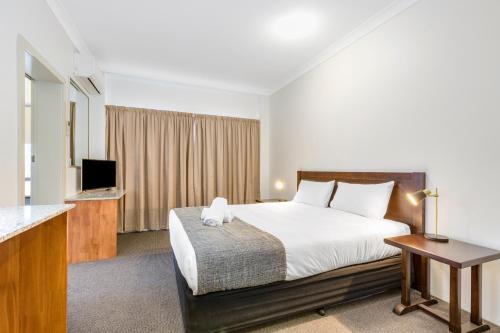 Habitación de hotel con cama y TV en Rockhampton Riverside Central Hotel Official en Rockhampton