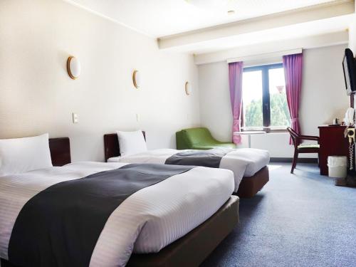 ein Hotelzimmer mit 3 Betten und einem Fenster in der Unterkunft Hotel Abest Happo Aldea in Hakuba