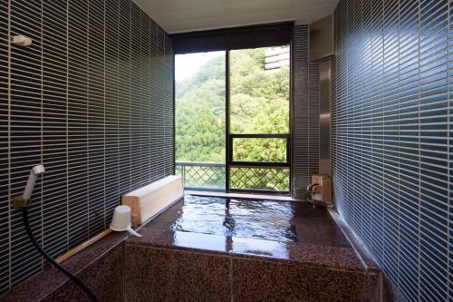 a bathroom with a tub and a window with a view at Hakone Nanase formerly known as Manatei Hakone in Hakone