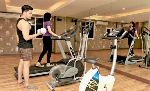 a man and woman in a gym with a exercise bike at Grand HAP Solo in Solo