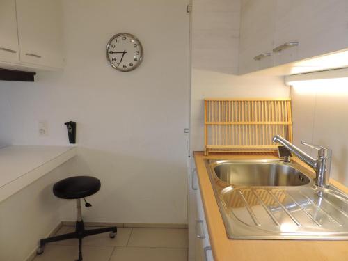 a kitchen with a sink and a clock on the wall at Astoria (175 Cl) in Lenzerheide