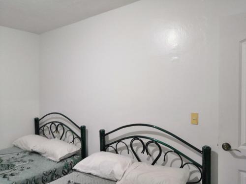 a bedroom with two beds with white pillows at Hostal Maple in Querétaro