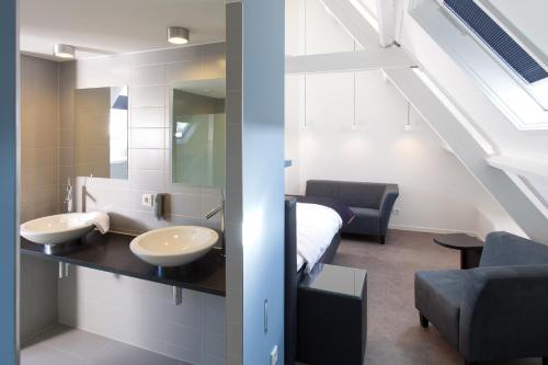 een badkamer met 2 wastafels en een bed in een kamer bij Boutique Hotel 't Lansink in Hengelo