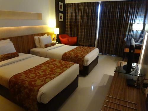 a hotel room with two beds and a chair at Hotel Satkar Residency in Thane