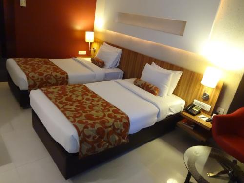 a hotel room with two beds and a chair at Hotel Satkar Residency in Thane