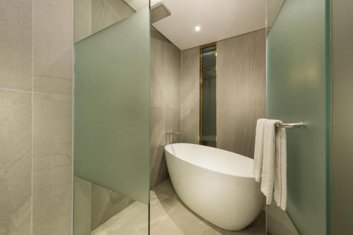 a bathroom with a bath tub and a glass wall at Hotel Peyto Gangnam in Seoul