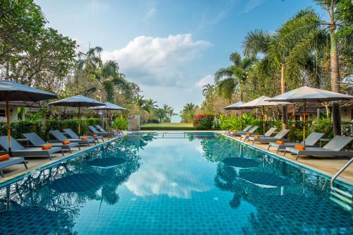 a pool at a resort with chairs and umbrellas at Bandara On Sea, Rayong in Klaeng