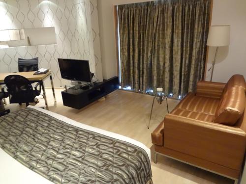 a bedroom with a bed and a desk and a couch at Hotel Satkar Residency in Thane