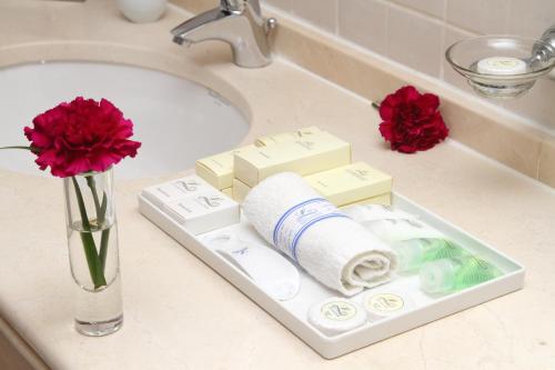 a bathroom sink with a tray with toiletries and flowers at Lavender Hotel Sharjah in Sharjah