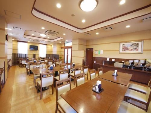 a dining room with wooden tables and chairs at Hotel Route-Inn Kikugawa Inter in Kikugawa