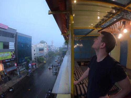 a man standing on a balcony looking at a city street at The Little Blue Window Hostel in Bengaluru