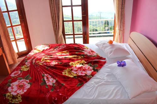 a bed with a red blanket on it with a window at The Mist Holiday Bungalow in Haputale