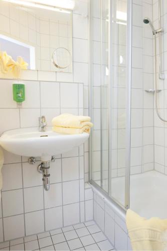a white bathroom with a sink and a shower at Caritas Tagungszentrum in Freiburg im Breisgau
