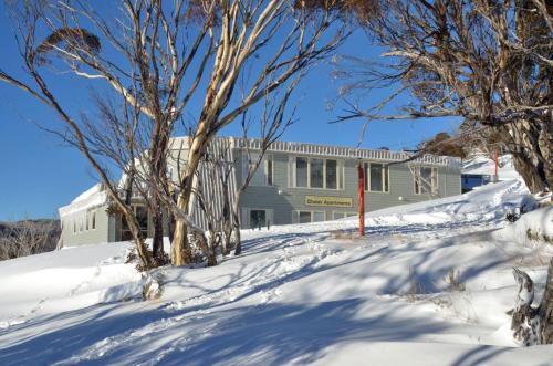 a building in the snow with trees in front at Smiggins Hotel & Chalet Apartments in Perisher Valley