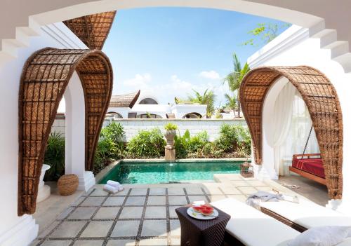 a villa with a swimming pool and an archway at Taj Bekal Resort & Spa, Kerala in Bekal