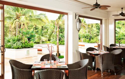 a restaurant with tables and chairs and palm trees at Taj Bekal Resort & Spa, Kerala in Bekal