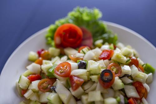 a white plate with a salad with tomatoes and lettuce at Alisa Hotel & Spa in Hanoi