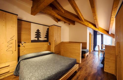 una camera con letto, pareti in legno e pavimenti in parquet di Hotel Al Plan Andalo ad Andalo