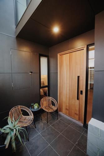 a room with two chairs and a wooden door at THE WAREHOUSE APARTMENTS in Geelong