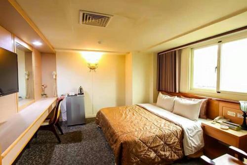 Pokój hotelowy z łóżkiem i biurkiem w obiekcie Lo Fo Hotel w mieście Taizhong
