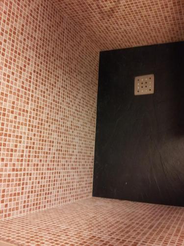 a bathroom with a black door with a tiled wall at La Brisa de Tarik Rooms in Tarifa