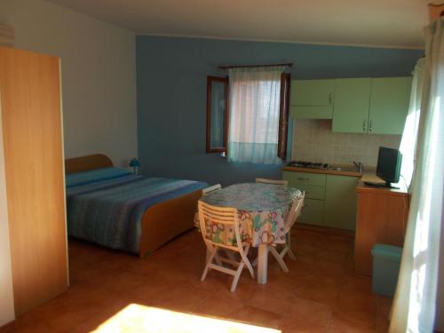 a bedroom with a bed and a table and a kitchen at Agriturismo Ezzi Mannu in Stintino