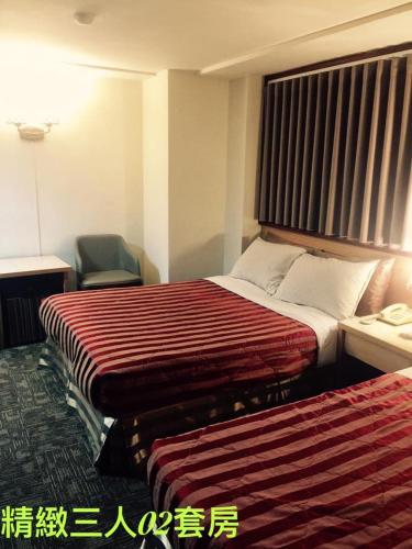 a hotel room with two beds and a chair at Lo Fo Hotel in Taichung