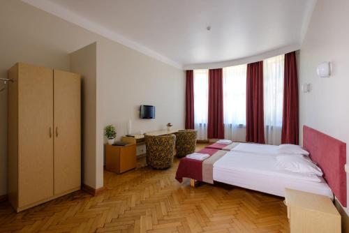 a bedroom with a bed and a desk in a room at Hotel Metropolis in Kaunas