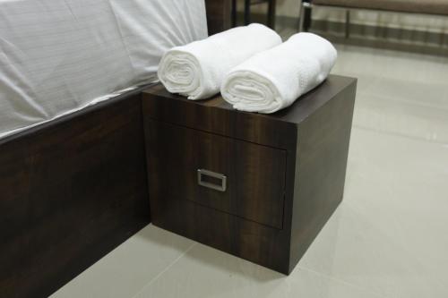 2 toallas enrolladas sobre una caja de madera con toallas en Shivalaya Residency, en Trichūr