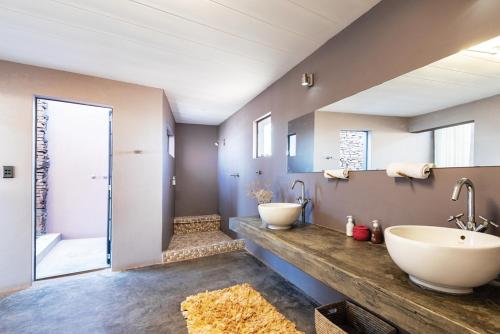 łazienka z 2 umywalkami i dużym lustrem w obiekcie Fish River Lodge w mieście Ariamab