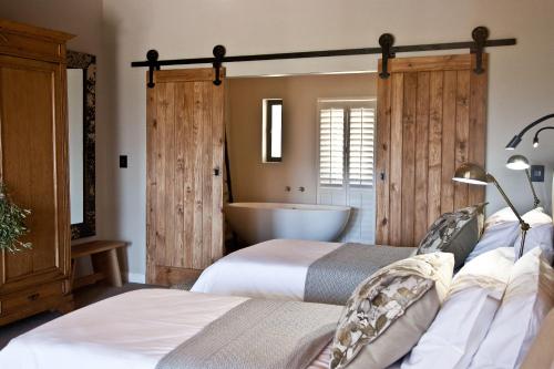 a bedroom with two beds and a bath tub at d'Olyfboom Guest House B & B in Paarl