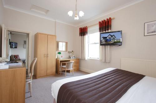 a bedroom with a bed and a desk and a table at BEST WESTERN New Holmwood Hotel in Cowes
