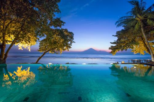 a swimming pool with a view of the ocean and a mountain at Jeeva Klui Resort in Senggigi