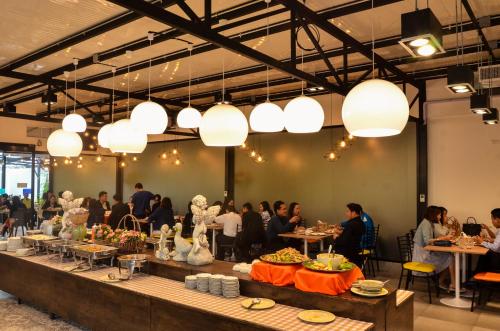 een groep mensen die aan tafel zitten in een kamer met verlichting bij At Ruam Chok Hotel in Chiang Mai