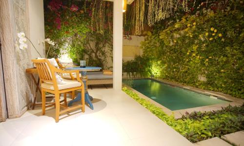 a small swimming pool with a table and chairs in a garden at Villa Bali Asri Batubelig in Seminyak