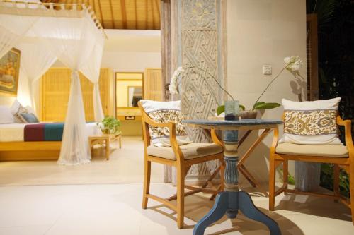 a room with a bed and a table and chairs at Villa Bali Asri Batubelig in Seminyak