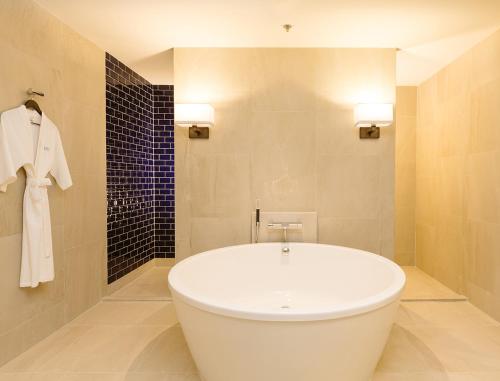 uma banheira branca numa casa de banho com azulejos em Modena by Fraser Buriram em Buriram